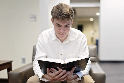 male student reading the bible