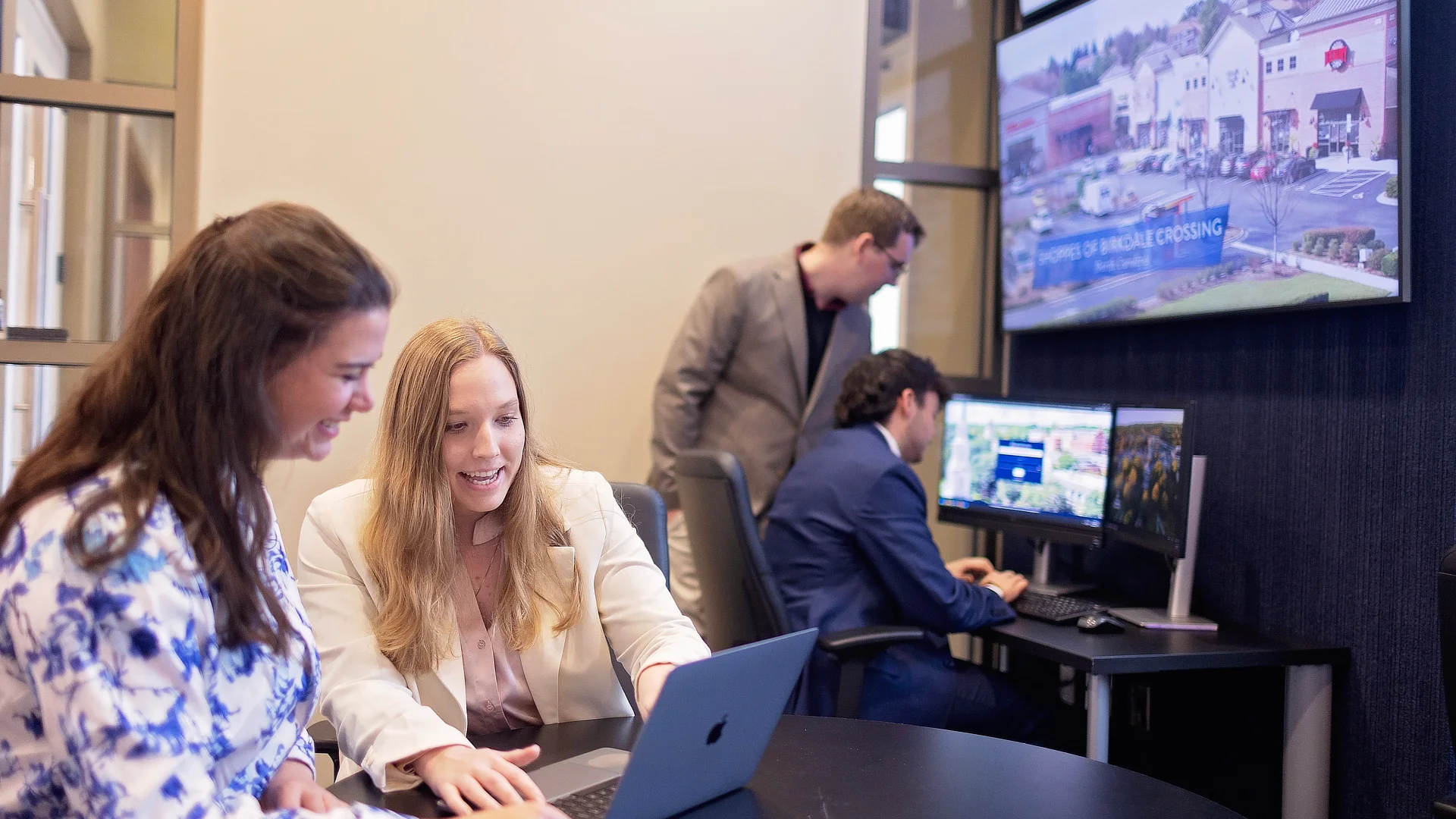 four students working on laptops in computer lab