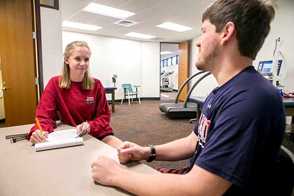 Female student interviewing male student for testing