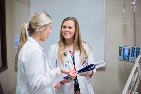 two female pharmacists talking at bedside