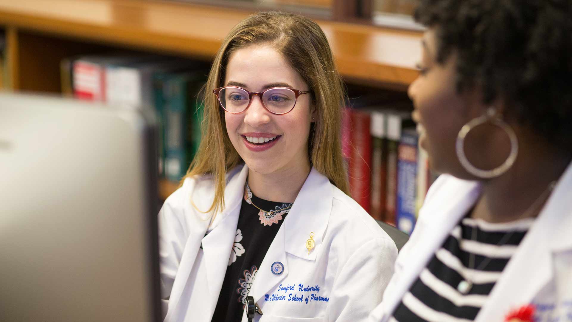 white and black female pharmacy students at computer