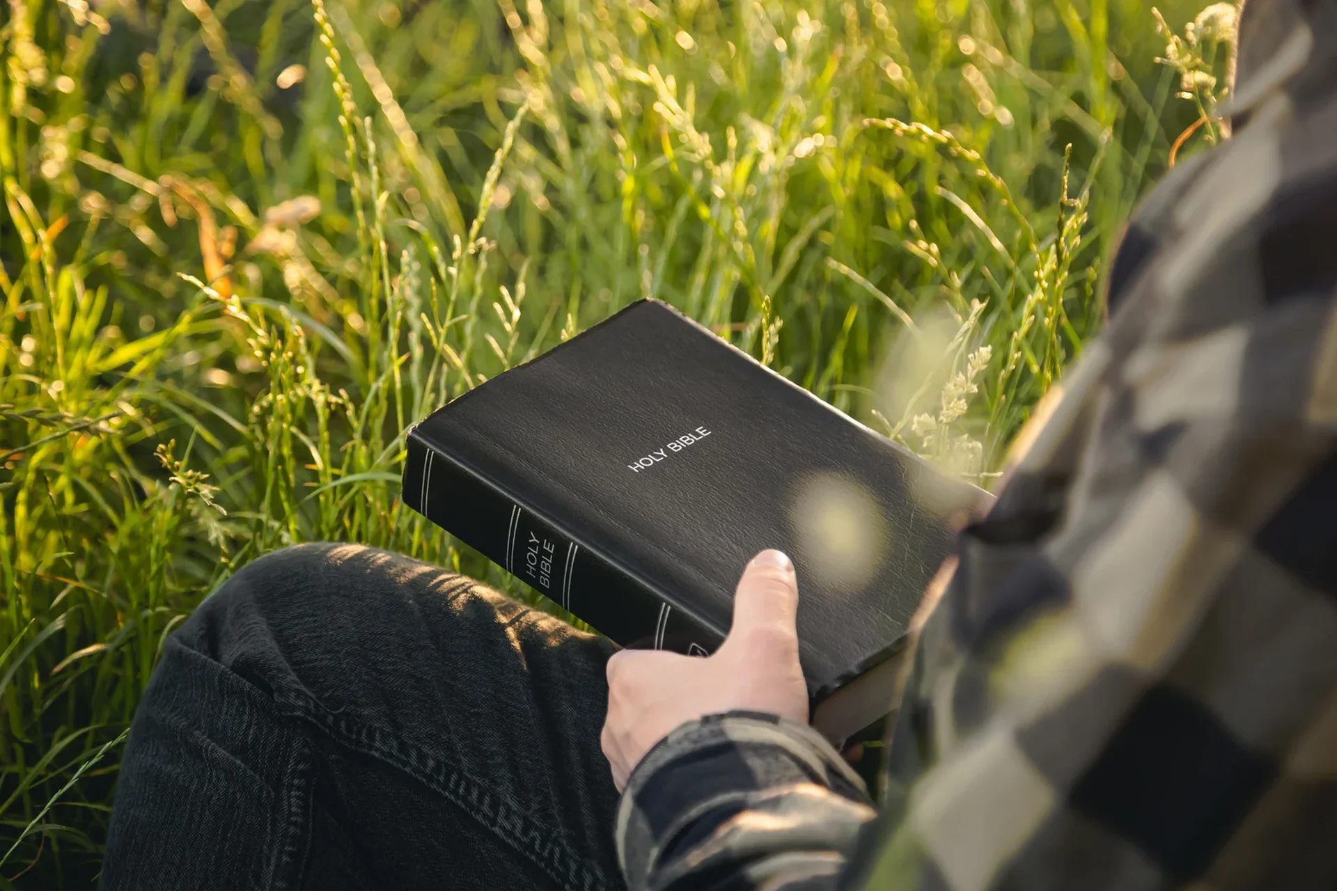 Man Reading Holy Bible in Field